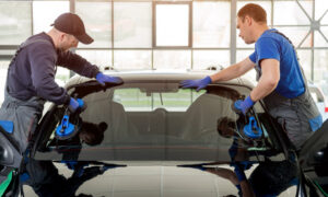 Two workers installing a car windscreen in a factory/workshop