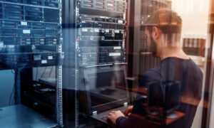 Developer sitting at computer with server in background