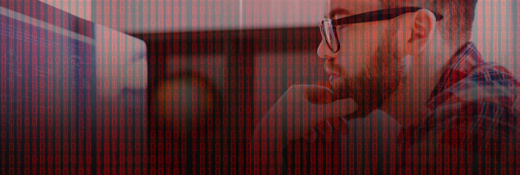 Profile view of man scratching chin while looking at a computer screen, superimposed with cyber security red binary numbers