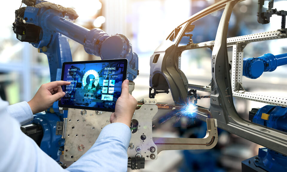 Man holding up a tablet which is controloing a factory machine
