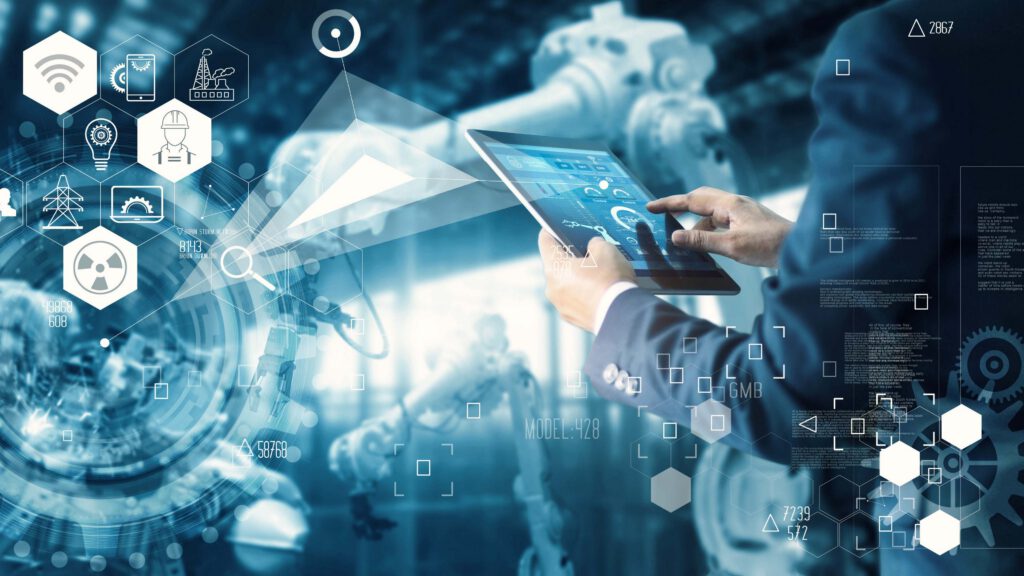Man in a suit controlling industrial robots using a tablet. Industrial icons are overprinting the image.