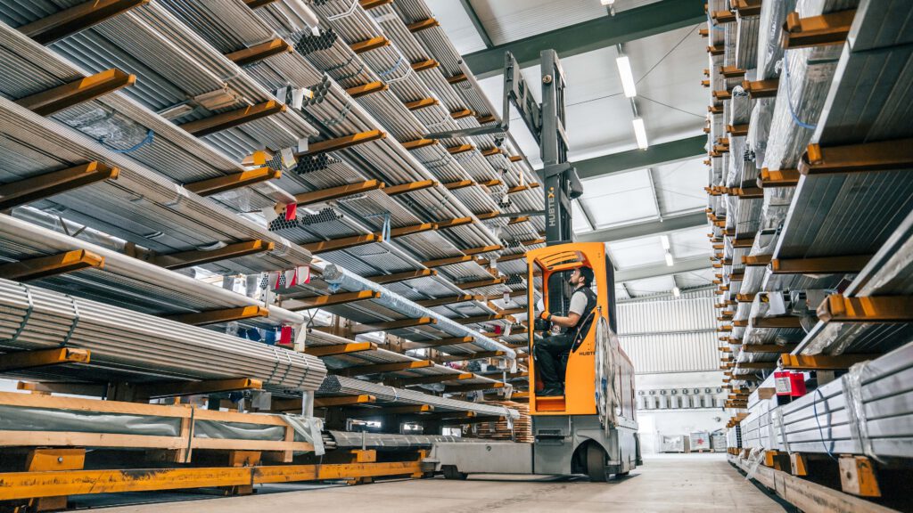 Inside a steel warehouse with a man driving a forklift